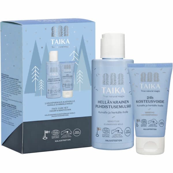 A light blue Taika Sensitive Face Care Set box with white trees is shown next to two Taika natural cosmetics: a Sensitive Cleansing Milk bottle and a 24h fragrance-free moisturizer tube, for dry and sensitive skin.