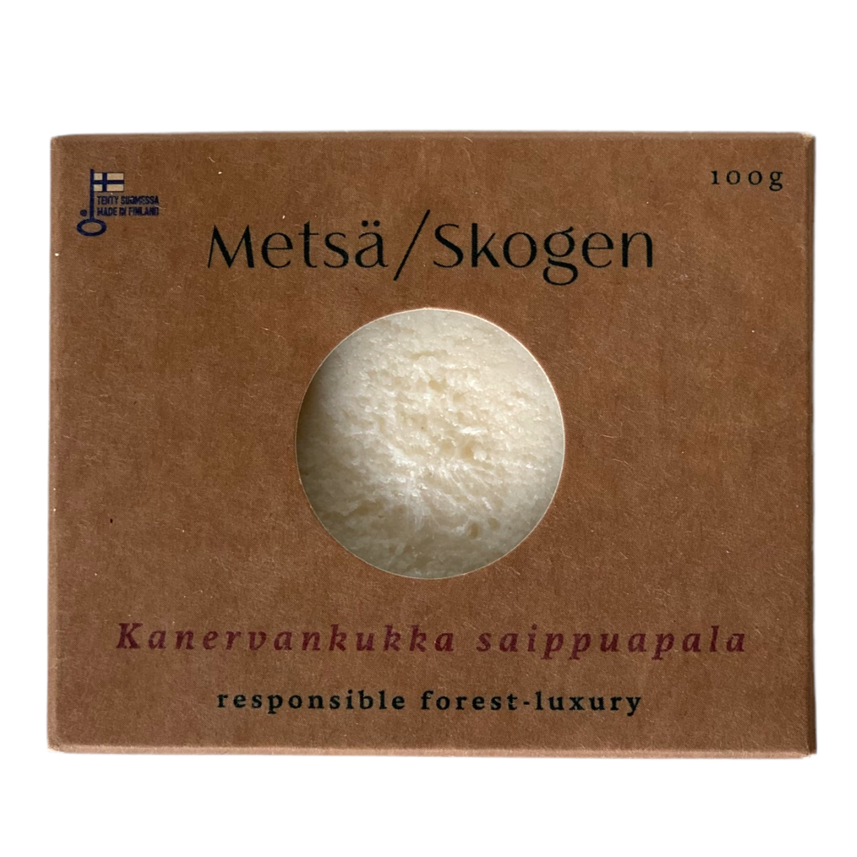 A brown cardboard box labeled Metsä/Skogen with a round cutout reveals the white Calluna Flower Salt Soap (100g) inside. Handcrafted in Finland, it features Himalayan rose salt and offers responsible forest-luxury.