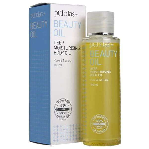 A bottle of Puhdas+ Beauty Deep Moisturising Body Oil (100 ml) stands next to its box, both with blue and gold text. The packaging highlights “pure & natural,” Finnish superberries, and a “100% pure” seal.