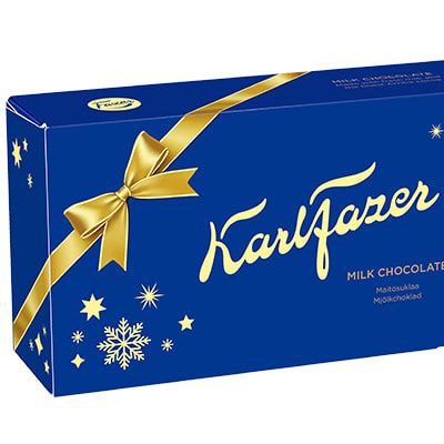 Eine festliche blaue Schachtel Fazer Milk Chocolate Praline Xmas Edition, verziert mit gelben Akzenten, Schneeflocken, einer großen Schleife und goldener Schrift; rechts die ausgepackten und eingepackten Pralinen - ein ideales finnisches Weihnachtsgeschenk von Fazer.