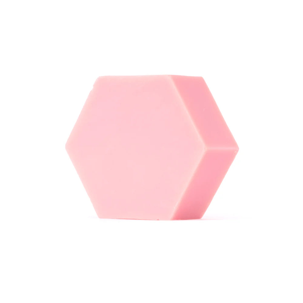 Die Luonkos Glow Devotion Hand- und Körperseife, ein sechseckiger veganer Riegel in kräftigem Rosa, ist auf einem schlichten weißen Hintergrund abgebildet.