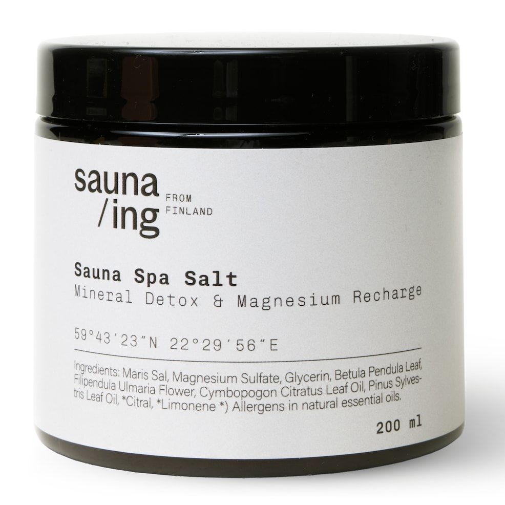 Ein schwarzer 200-ml-Tiegel mit Sauna/ing-Sauna-Spa-Salz von sauna/ing hat ein weißes Etikett mit Produktdetails und Inhaltsstoffen - ideal für ein entgiftendes Bad oder ein entspannendes Fußbad.