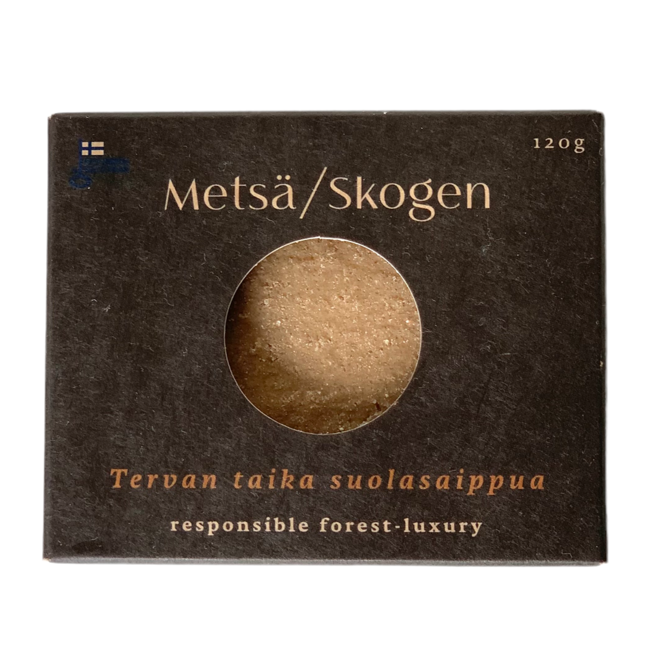 Die Schachtel der Metsä/Skogen Magic of Tar Salt Soap (120 g) hat ein rundes Fenster, in dem die Seife präsentiert wird. Die Verpackung betont den verantwortungsvollen Wald-Luxus und die authentische finnische Teersalzseife von Metsä/Skogen.