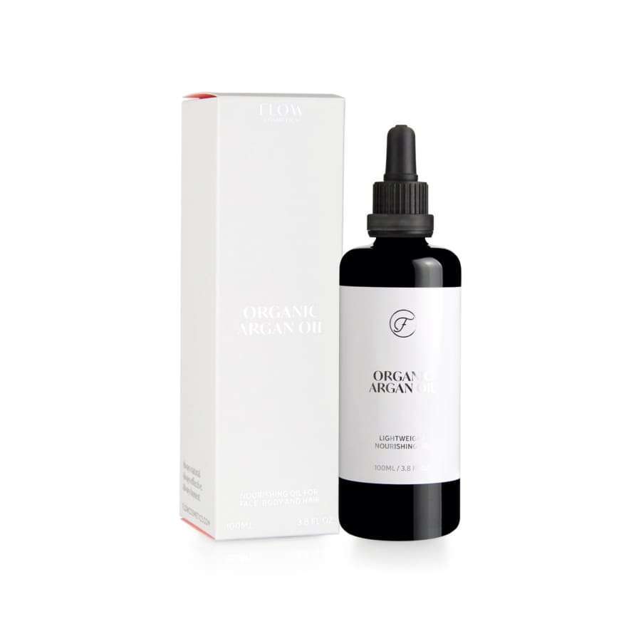 Ein schwarzer Flakon von FLOW Cosmetics Bio-Arganöl mit Tropfverschluss steht neben der passenden weißen, minimalistischen Schachtel. Auf dem Etikett steht "Organic Argan Oil" und "Lightweight Nourishment", ideal für empfindliche Haut. Marke: Flow Cosmetics.