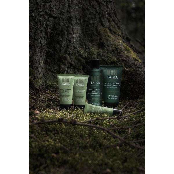 Die Taika Night Cream von Taika steht auf üppigem Moos am Fuße eines großen Baumes in einem düsteren Wald und fügt sich ganz natürlich in die Umgebung ein.