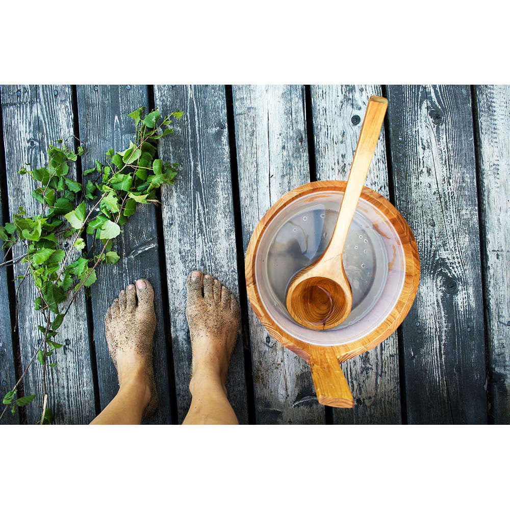 I piedi nudi sulla sabbia poggiano su assi consumate dal tempo accanto a un secchio e un mestolo di legno, mentre una fragranza Emendo Sauna (eucalipto, betulla, sauna affumicata e catrame) riempie l'aria di profumi rinfrescanti e oli essenziali.