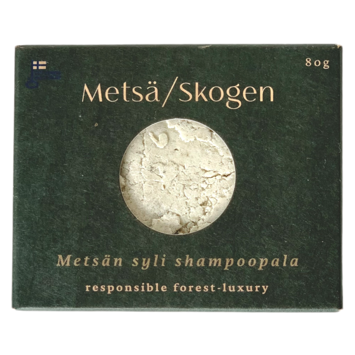 Een donkergroene Metsä/Skogen-doos met een rond venster toont de Lap of the Forest Shampoo Bar voor vet haar. De tekst luidt: Metsän syli shampoopala, verantwoord bosluxe, handgemaakt in Finland, en 80 g rechtsboven.