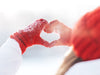Woman with red gloves and knit cap making a heart between hands