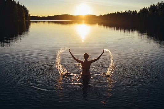 Une femme nageant dans un lac en Finlande au coucher du soleil