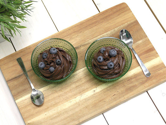 Two portions of ketogenic chocolate-avocado mousse served with blueberries