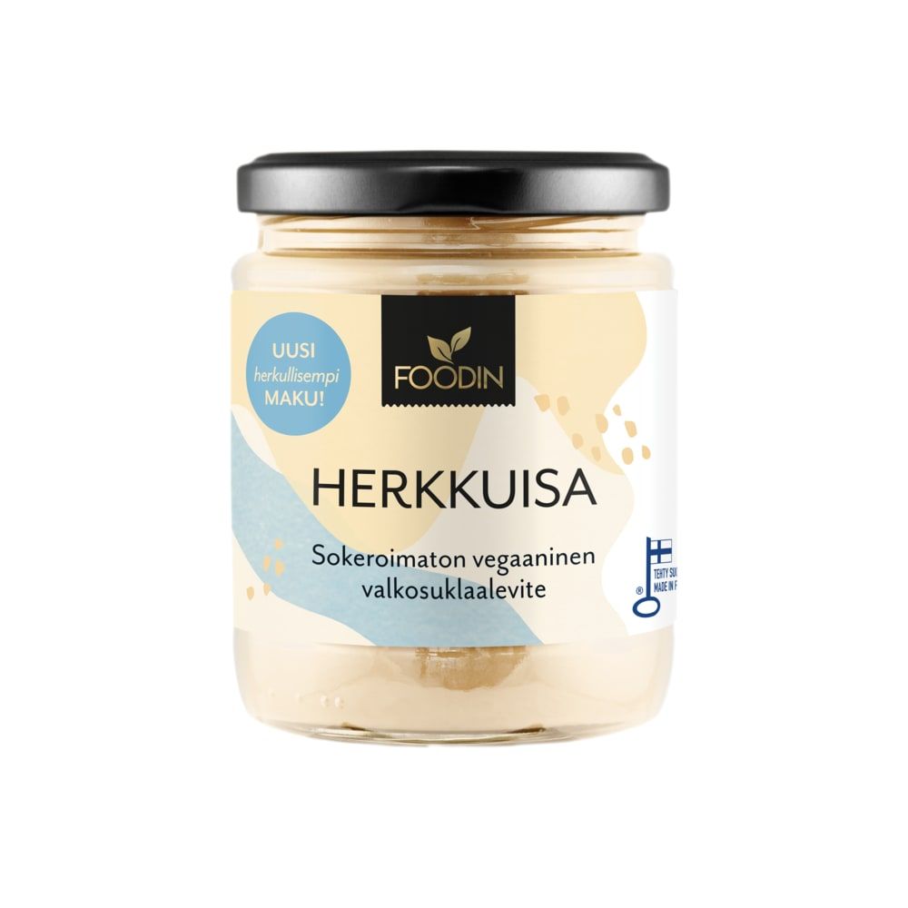A glass jar of Foodin Herkkuisa White Chocolate Spread Sugar Free with a black lid and colorful Finnish label, indicating it is a vegan, sugar free spread without added sugar.