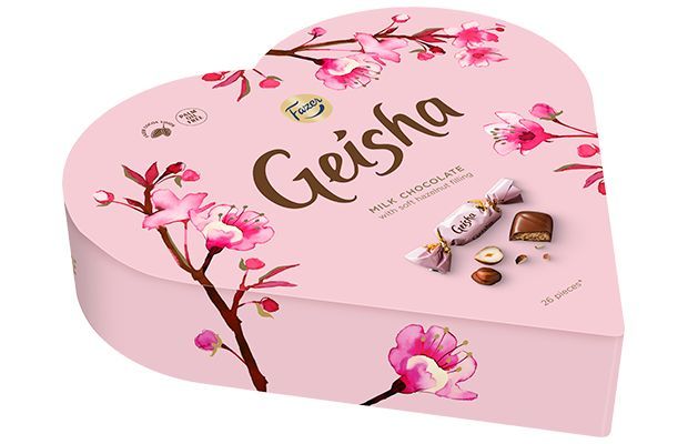 The Fazer Geisha Gift Box is a heart-shaped pink box of Finnish chocolate, decorated with cherry blossom art, the Geisha logo, and images of milk chocolate with hazelnut filling by Fazer.