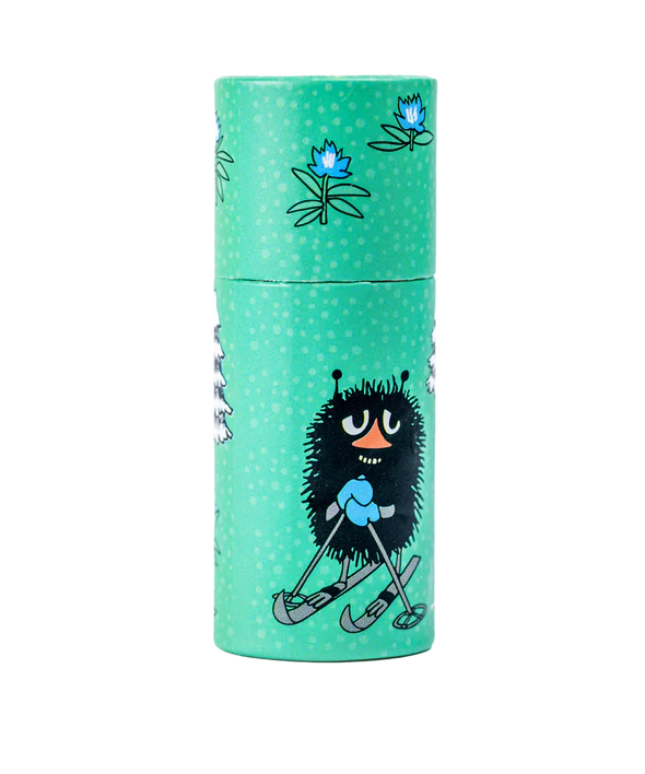 The Gustaf & Linnea Moomin Lipbalm Stinky comes in a green cylinder with white dots, blue flowers, and a cartoon black fuzzy Stinky in blue mittens and skis—an adorable way to carry your eco-friendly lip balm.