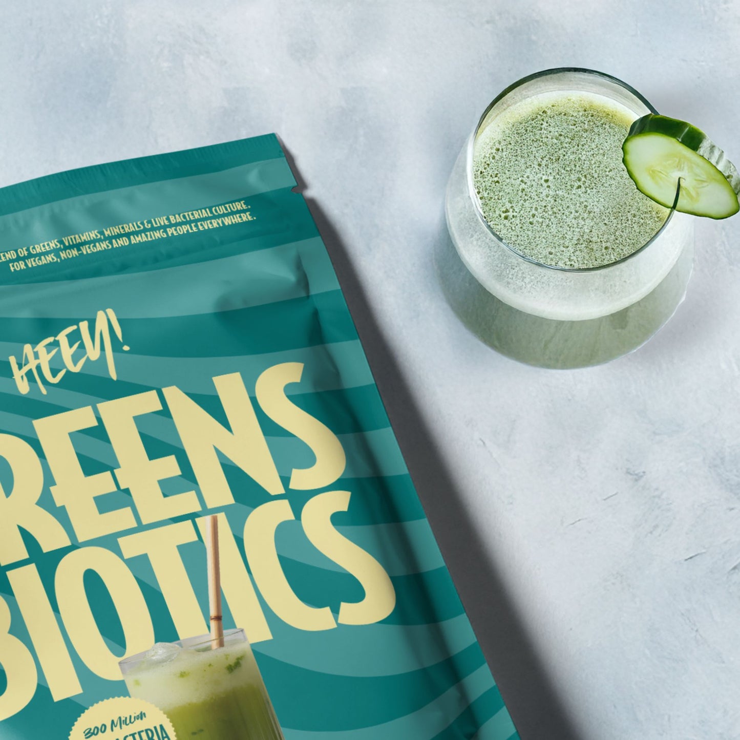 Heey! Greens & Biotics package with a glass of green smoothie on a light gray background