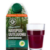 A green carton of Kari's Pine Extract Drink 6-pack stands beside a clear glass of dark red juice. The box features Finnish pine forest imagery and displays organic and health badges, highlighting its antioxidant-rich pine extract.