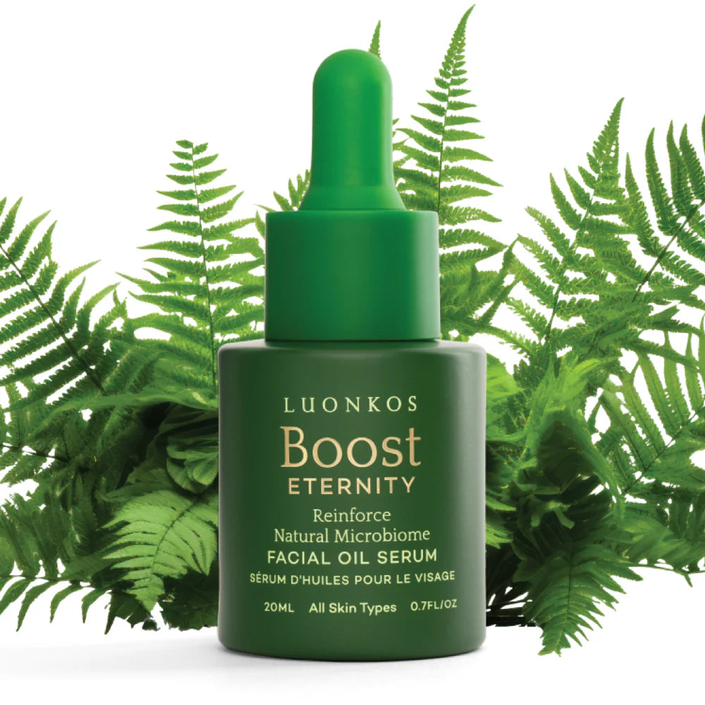 A green dropper bottle labeled Luonkos Eternity Facial Oil Serum rests among lush ferns. The text highlights its natural microbiome, Finnish forest microbe extract, and suitability for all skin types. Brand: Luonkos.