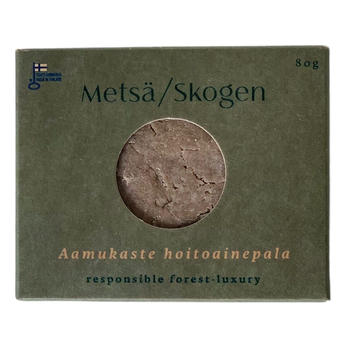 A green Metsä/Skogen box with a round window displays a brown solid. Text reads: Metsä/Skogen Morning Mist Conditioning Bar, sensitive scalp conditioner, responsible forest luxury, handcrafted in Finland, 80g.
