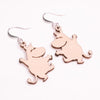 The Coruu Moomin Wooden Earrings by Coruu are Nordic-style wooden earrings shaped like smiling cartoon hippos with raised arms, featuring metal hooks and shown on a white background.