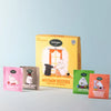 Nordket Moomin Besties coffee pouches displayed in front of their yellow illustrated box on a light gray background. The set includes pink, brown, green, and orange pouches featuring Moomin characters.