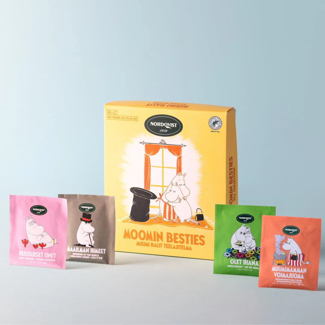 Nordket Moomin Besties coffee pouches displayed in front of their yellow illustrated box on a light gray background. The set includes pink, brown, green, and orange pouches featuring Moomin characters.