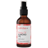 A bottle of puhdas+ Beauty Oil Almond Oil, featuring an amber glass bottle with a black spray pump and a white label with pink accents, set against a plain white background.
