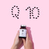 Twee handen houden een flesje Puhdistamo High-Strength Q10 Ubiquinone 150 mg vast; bovenop staan zwarte capsules op een roze achtergrond met de letters 'Q10', waarmee de rol van Puhdistamo in het ondersteunen van het energiemetabolisme met dit krachtige ubiquinonesupplement wordt benadrukt.