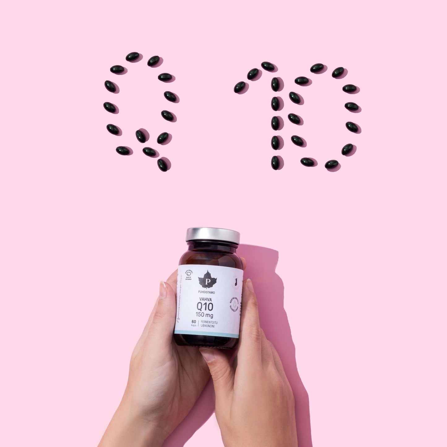Twee handen houden een flesje Puhdistamo High-Strength Q10 Ubiquinone 150 mg vast; bovenop staan zwarte capsules op een roze achtergrond met de letters 'Q10', waarmee de rol van Puhdistamo in het ondersteunen van het energiemetabolisme met dit krachtige ubiquinonesupplement wordt benadrukt.