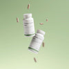 Two white bottles labeled "THERA Nordic Move" float against a soft green gradient with capsules suspended around them, highlighting this THERA Nordic magnesium supplement that supports healthy bowel movements in a clean, minimalist scene.