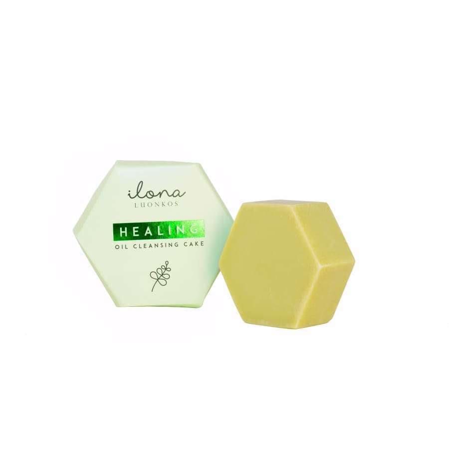 A hexagonal yellow Luonkos Healing Oil Cleansing Cake made with natural ingredients sits by its light green Luonkos packaging, ideal as a gentle facial cleanser for oily skin, on a white background.