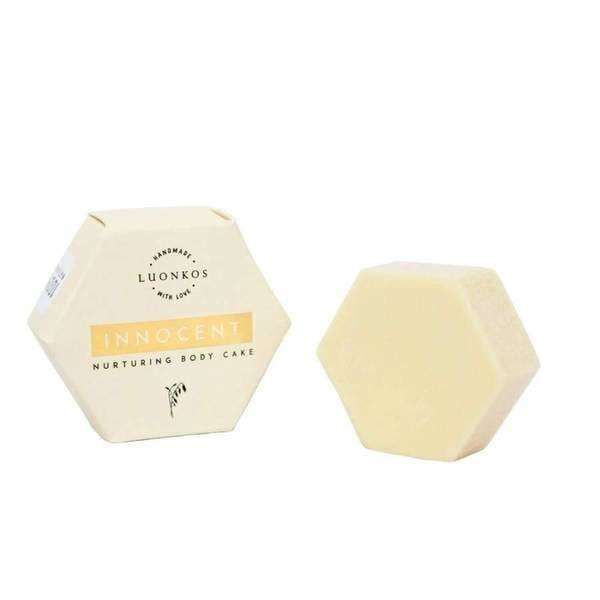 A hexagonal pale yellow Luonkos Innocent Nurturing Body Cake sits beside its matching cream box, both labeled Luonkos and made with natural ingredients for dry and sensitive skin.