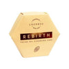 A beige hexagonal box labeled Luonkos Rebirth Oil Cleansing Cake, featuring a cocoa bean icon and "Handmade with love" above the Luonkos brand—an all-natural facial cleanser perfect for vegan skincare routines.