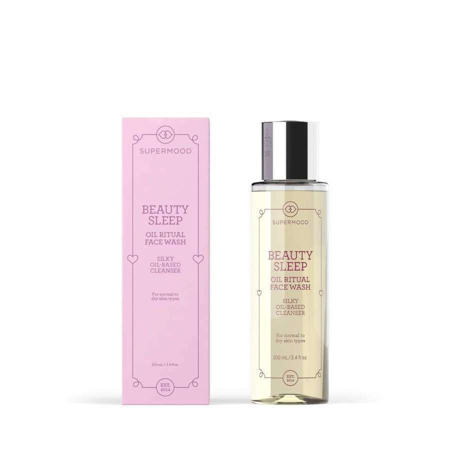A bottle of Supermood Beauty Sleep Oil Ritual Face Wash stands beside its pink box; the bottle has a silver cap and clear label with gold and black text on a white background.