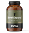 A brown bottle labeled DENSE Beef Organs shows a cow head silhouette and contains 180 capsules (400 mg each) of freeze-dried organ supplements. The label reads 100% Animal-Based dietary supplement by DENSE.