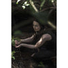 A woman crouches by a forest stream, cupping water in her hands as sunlight filters through the leaves above. Surrounded by greenery, she thinks of the refreshing purity of Taika Liquid Hand Soap by Taika.