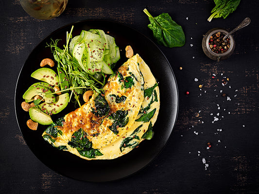 Ketogenic breakfast omelette with avocados, nuts, spinach and cucumber