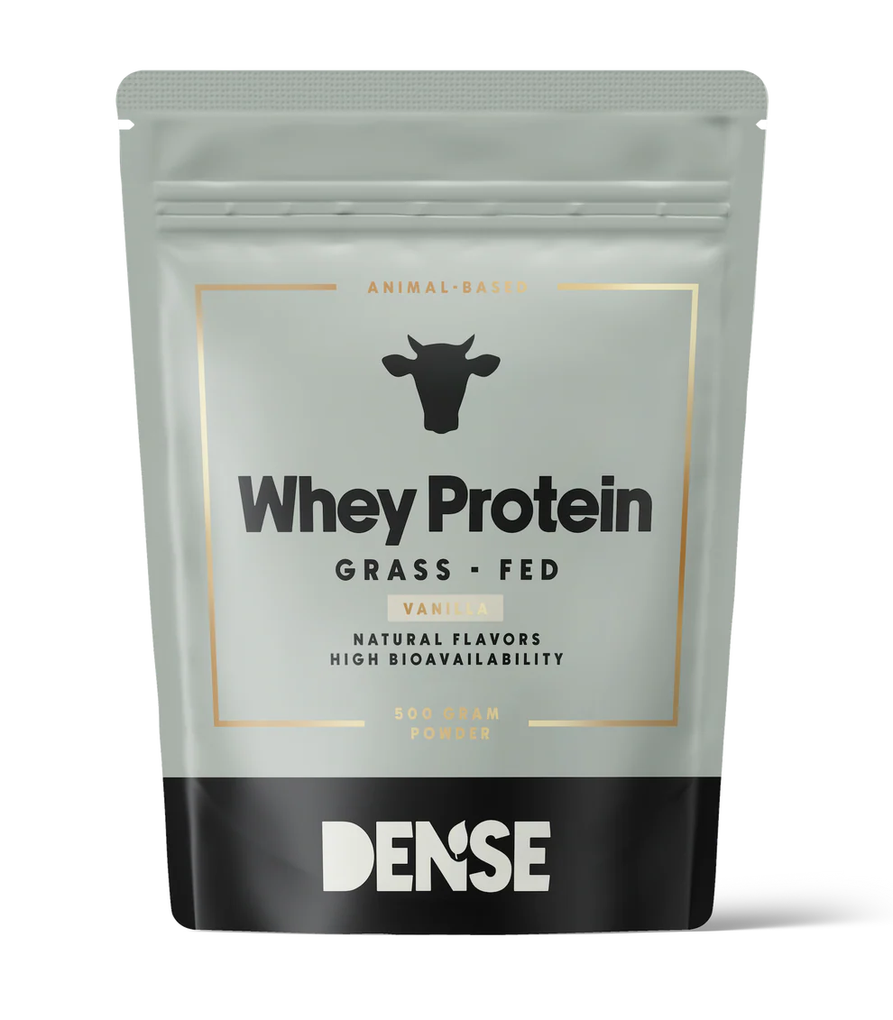 Ein grau-schwarzer Beutel mit DENSE Grass-Fed Whey Protein Vanilla (500 g), tierischen Ursprungs mit natürlichen Aromen und hoher Bioverfügbarkeit, zeigt ein Kuhsymbol auf der Verpackung und enthält Proteinpulver mit Vanillegeschmack.