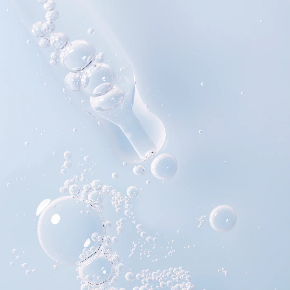 Eine Nahaufnahme eines Tropfers mit klaren Flüssigkeitsblasen vor einem hellblauen Hintergrund, der an die intensive Feuchtigkeitspflege und die klare Ästhetik von Lumene Nordic Hydra Aqua Serum von Lumene erinnert.