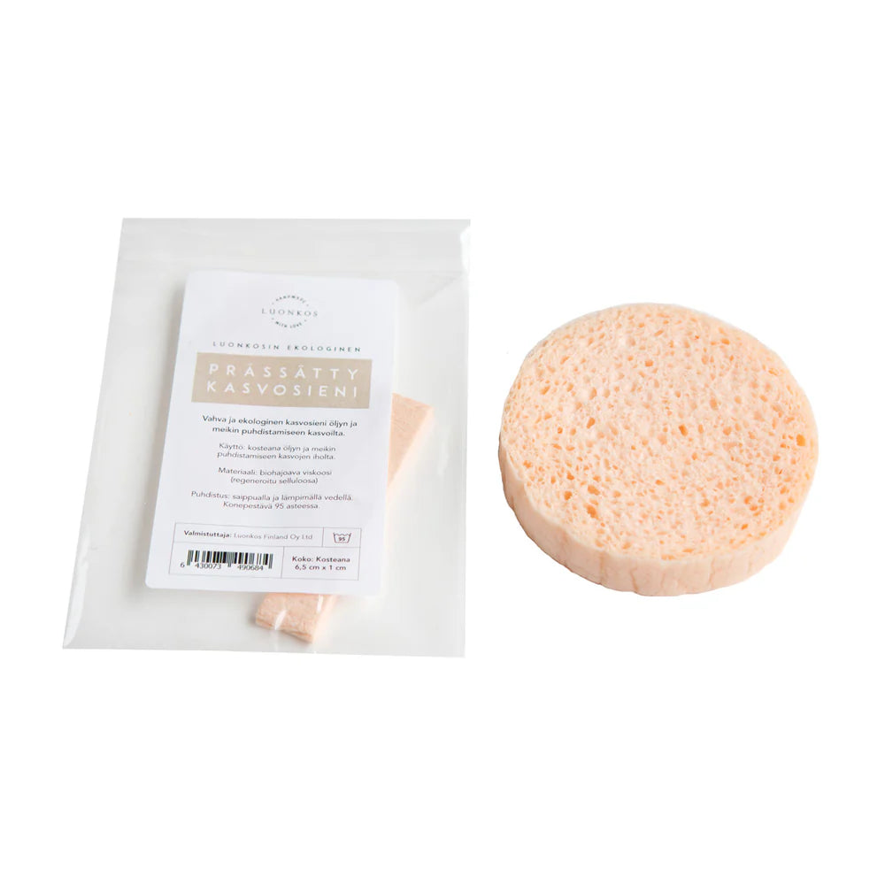 Der Luonkos Ecological Facial Cleansing Sponge, ein runder, hellbeiger, wiederverwendbarer Schwamm, wird unbenutzt neben seiner durchsichtigen Verpackung mit einem weißen Etikett mit finnischem Text präsentiert. Ideal für die Ölreinigung und umweltfreundliche Routinen. Marke: Luonkos.
