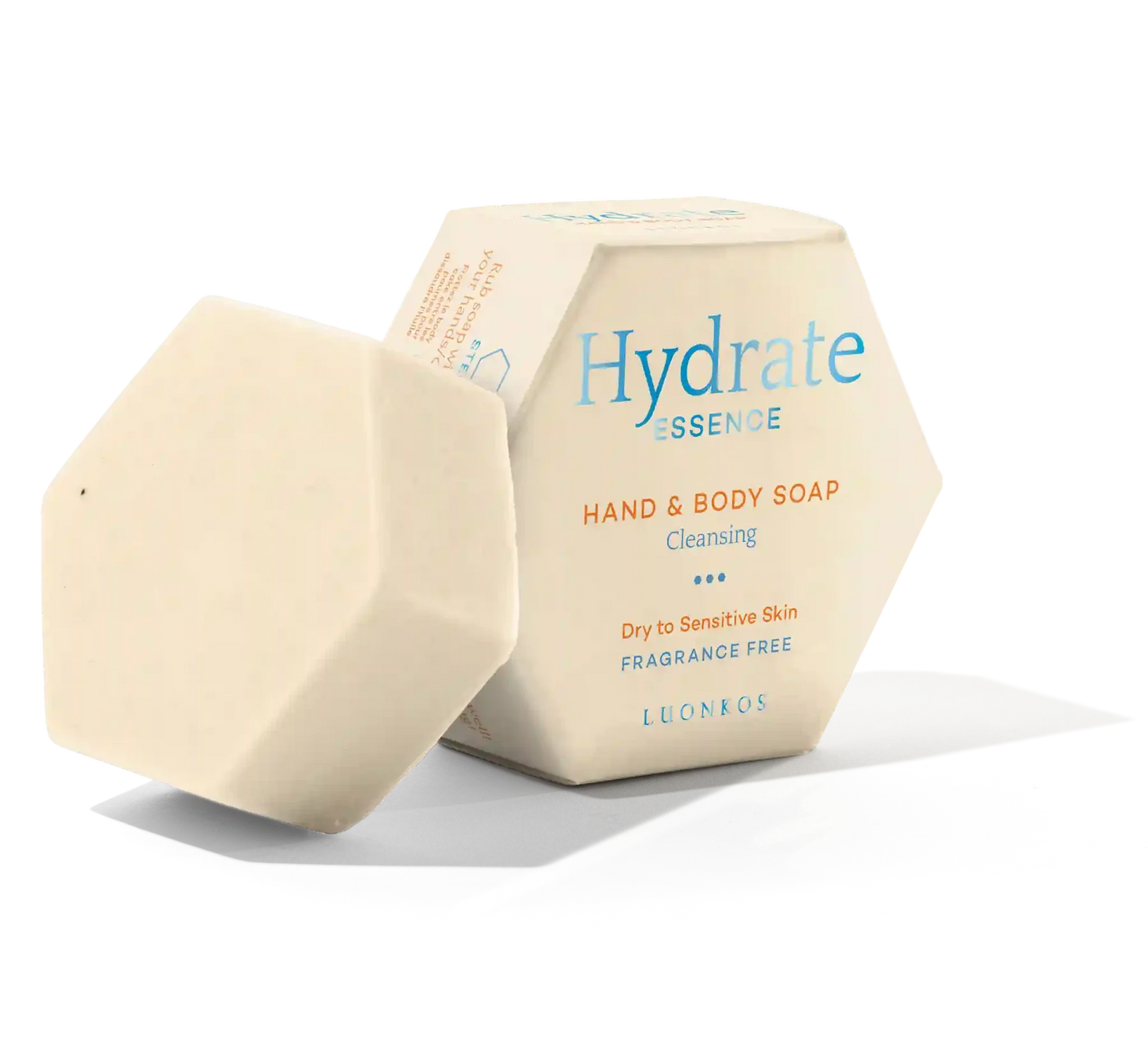 Ein cremefarbener, sechseckiger Seifenriegel der Luonkos Hydrate Essence Hand & Body Soap liegt neben der Schachtel. Die Seife ist parfümfrei und besteht aus natürlichen Pflanzenölen. Sie ist ideal für die Reinigung und Pflege trockener oder empfindlicher Haut.