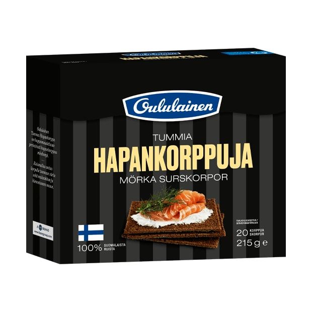 Eine Schachtel Oululainen Rye Crisp von Oululainen zeigt auf der Vorderseite ein mit Lachs und Dill belegtes Knäckebrot. Der ballaststoffreiche Snack kommt in einer schwarzen Verpackung mit weißem und braunem Text sowie einer finnischen Flagge.
