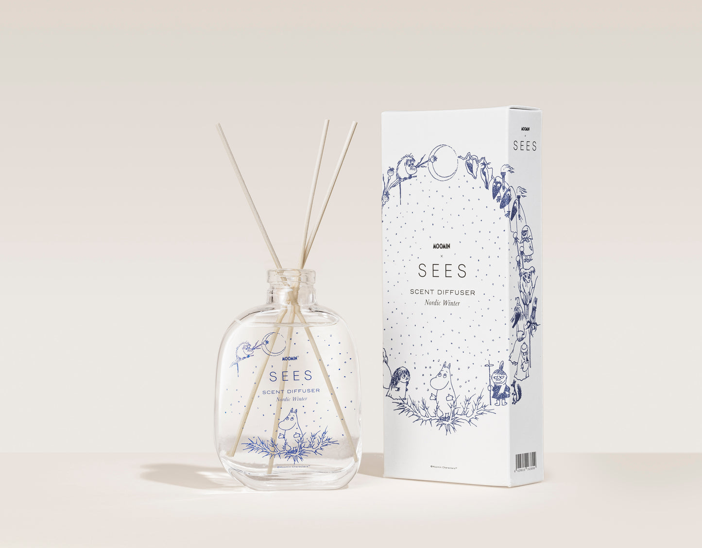 Der SEES Company Moomin Room Diffuser Nordic Winter besteht aus einer Glasflasche mit Holzstäbchen und einer dekorativen Schachtel mit verspielten blauen Motiven im finnischen Stil, beide mit der Aufschrift „SEES Scent Diffuser“.