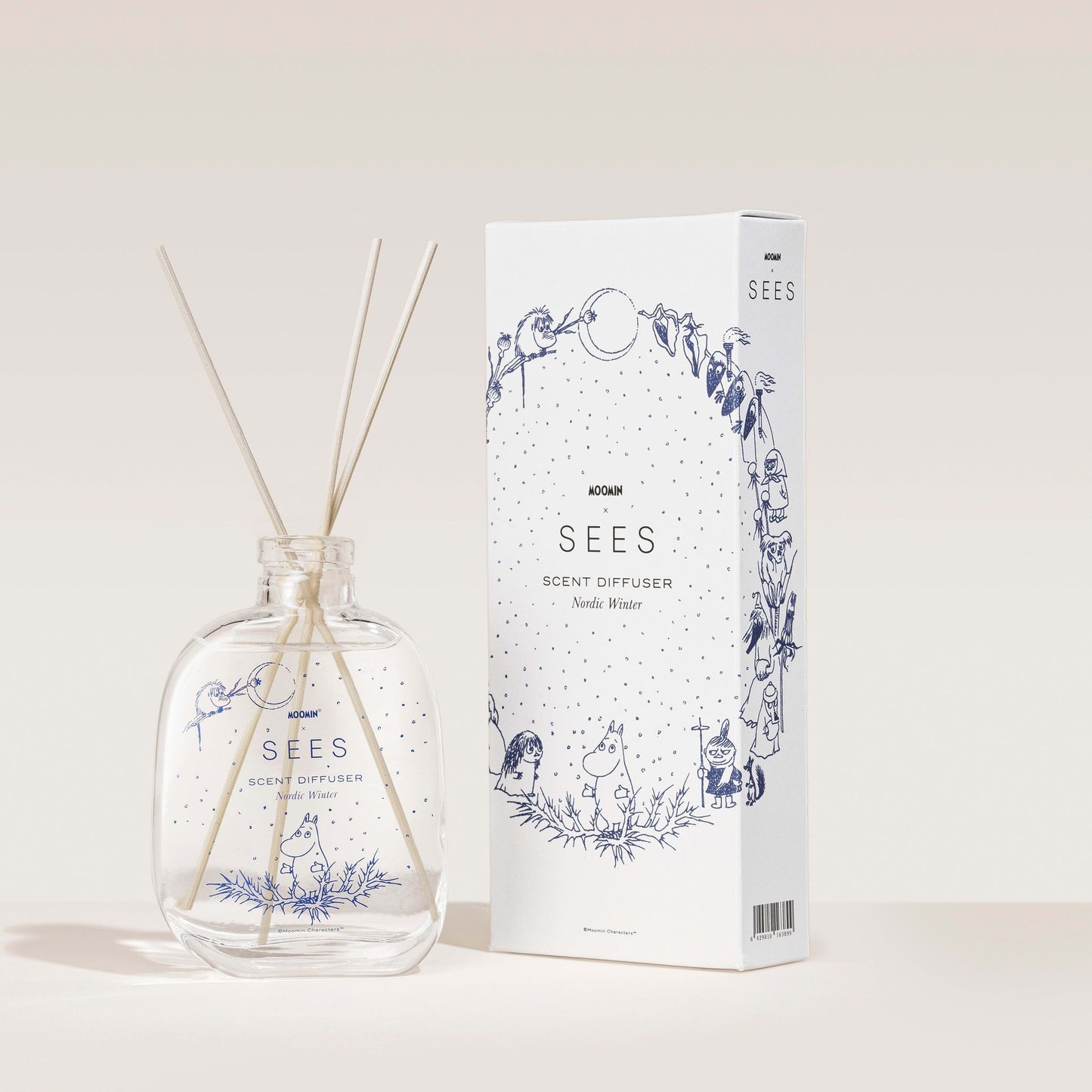 Der SEES Company Moomin Room Diffuser Nordic Winter besteht aus einer Glasflasche mit Holzstäbchen und einer dekorativen Schachtel mit verspielten blauen Motiven im finnischen Stil, beide mit der Aufschrift „SEES Scent Diffuser“.