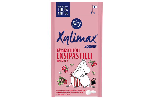 Die Fazer Xylimax Moomin Strawberry Full Xylitol Pastilles Verpackung zeigt eine Mumin-Figur mit Erdbeeren auf rosa Hintergrund. Die zahnfreundliche Süßigkeit ist mit finnischem und schwedischem Text versehen. Marke: Fazer.