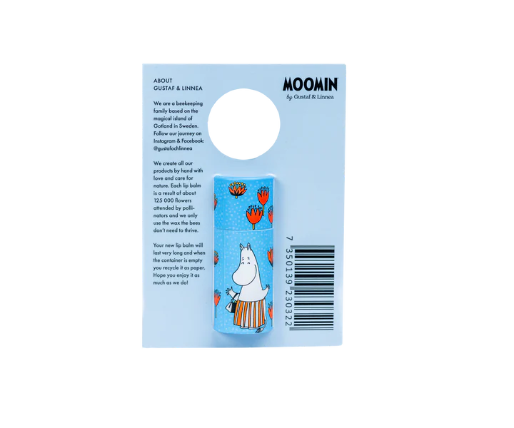 Le baume à lèvres Gustaf & Linnea Moomin Moominmamma est un baume à lèvres bleu et écologique dont l'emballage représente Moominmamma et des tulipes rouges. Le texte descriptif du produit, l'œillet de suspension et le code-barres se trouvent sur le côté droit.