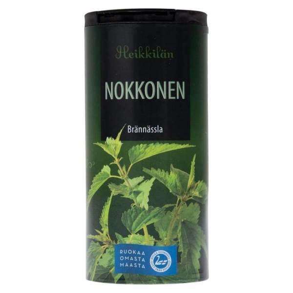 Un récipient cylindrique contenant la tisane aux orties de Heikkilä, riche en vitamines et en fer, présente des feuilles d'orties vertes. Le logo bleu RUOKAA OMASTA MAASTA figure au bas de l'emballage.