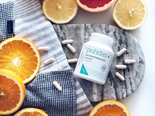 Prodotti a base di batteri Puhdas+ sul tavolo con fette d'arancia