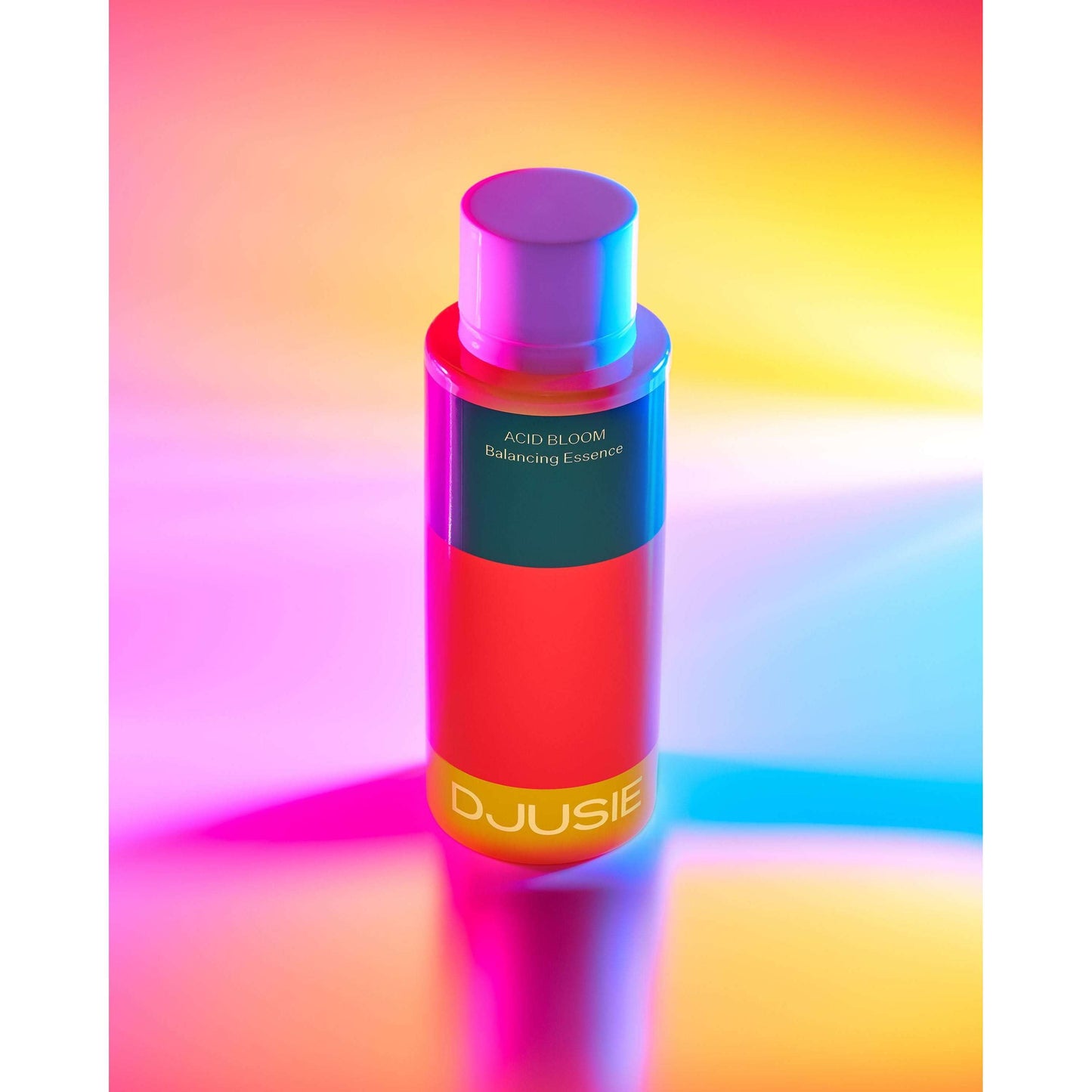 Una vivace bottiglia di Djusie Acid Bloom Balancing Essence è posizionata in verticale su uno sfondo multicolore, mettendo in risalto l'effetto illuminante di questa essenza Djusie e il suo sostegno al naturale equilibrio del pH della pelle.