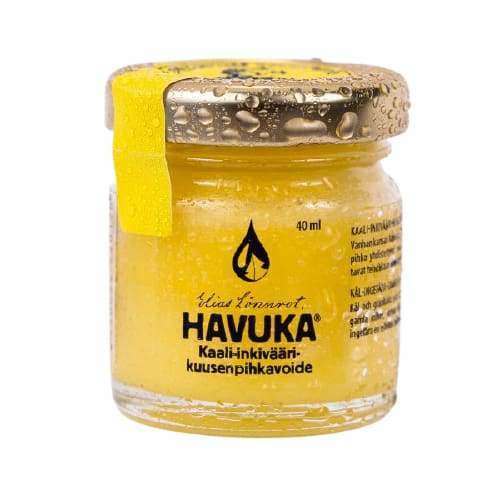 Un piccolo barattolo di vetro contenente Havuka Cabbage-Ginger-Spruce Resin Balm, un unguento naturale per le articolazioni prodotto da Havuka, con condensa sul coperchio e sul barattolo, un sigillo giallo sul lato sinistro e testo in finlandese.