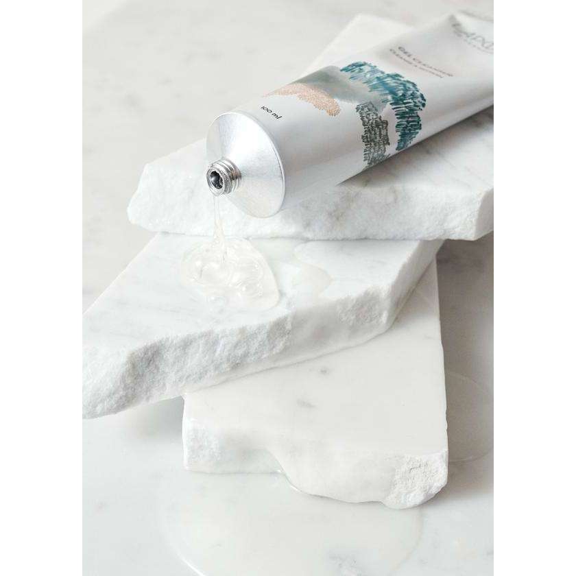 Een open tube Laponie of Scandinavia Cleanser ligt op gestapelde witte marmeren platen, met gel die op het oppervlak sijpelt. Deze minimalistische, elegante opstelling benadrukt dat het product geschikt is voor de gevoelige huid.