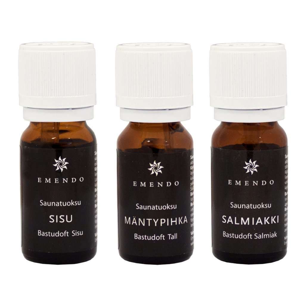 Drie kleine Emendo-flesjes met het label 'Emendo Sauna Fragrance Salmiac, Pine & Sisu' bevatten in Finland geproduceerde saunageuren. De bruine glazen flesjes hebben witte doppen en zwarte etiketten met witte Finse tekst.